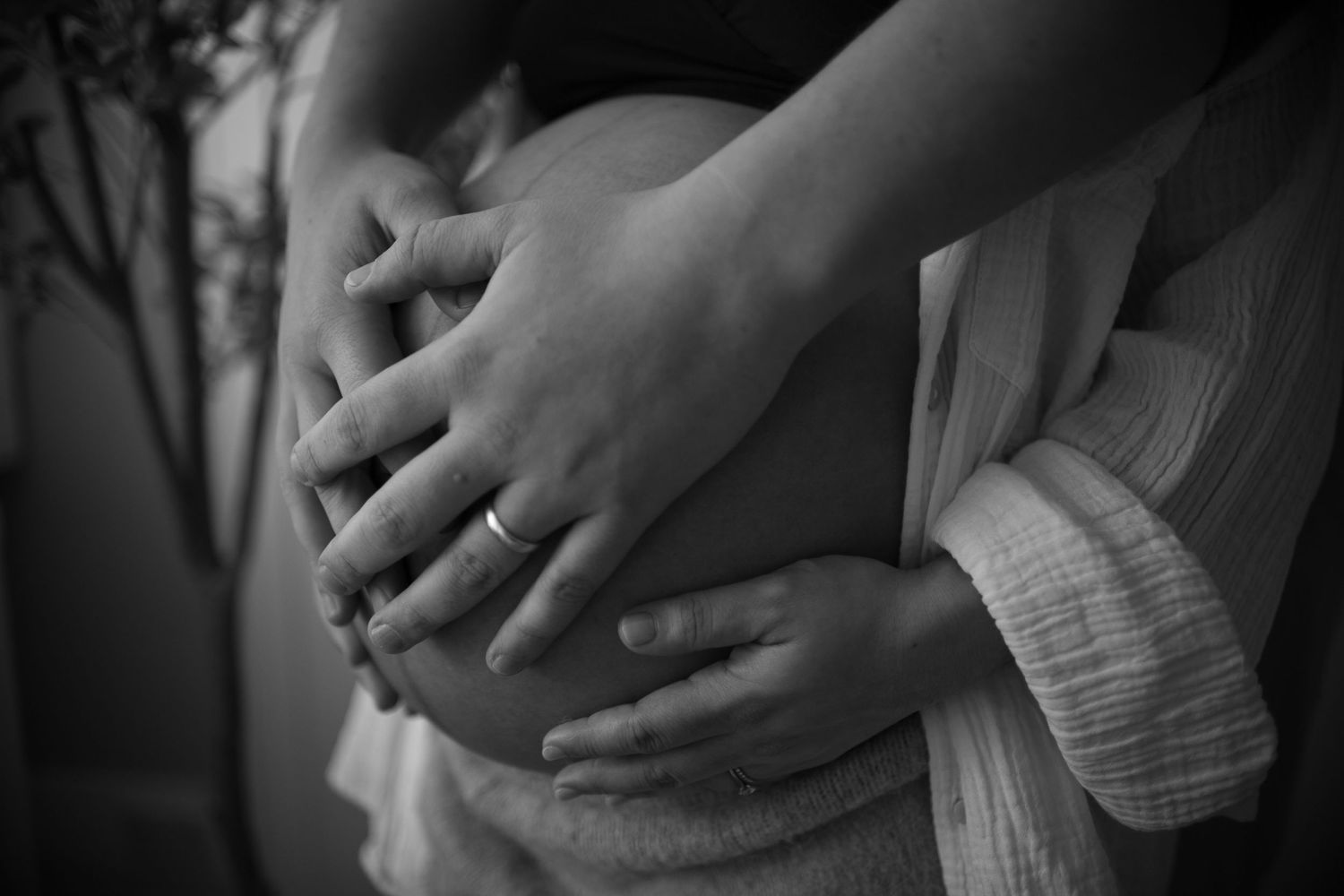 Black and white photos of hands gently cradling a pregnant belly.