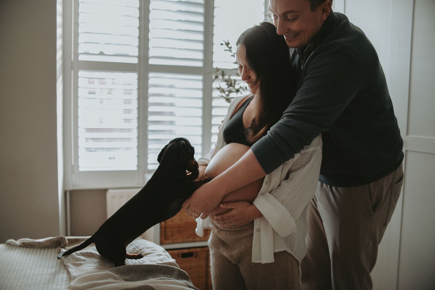 Black and white series of intimate pregnancy photos near a window with natural light.