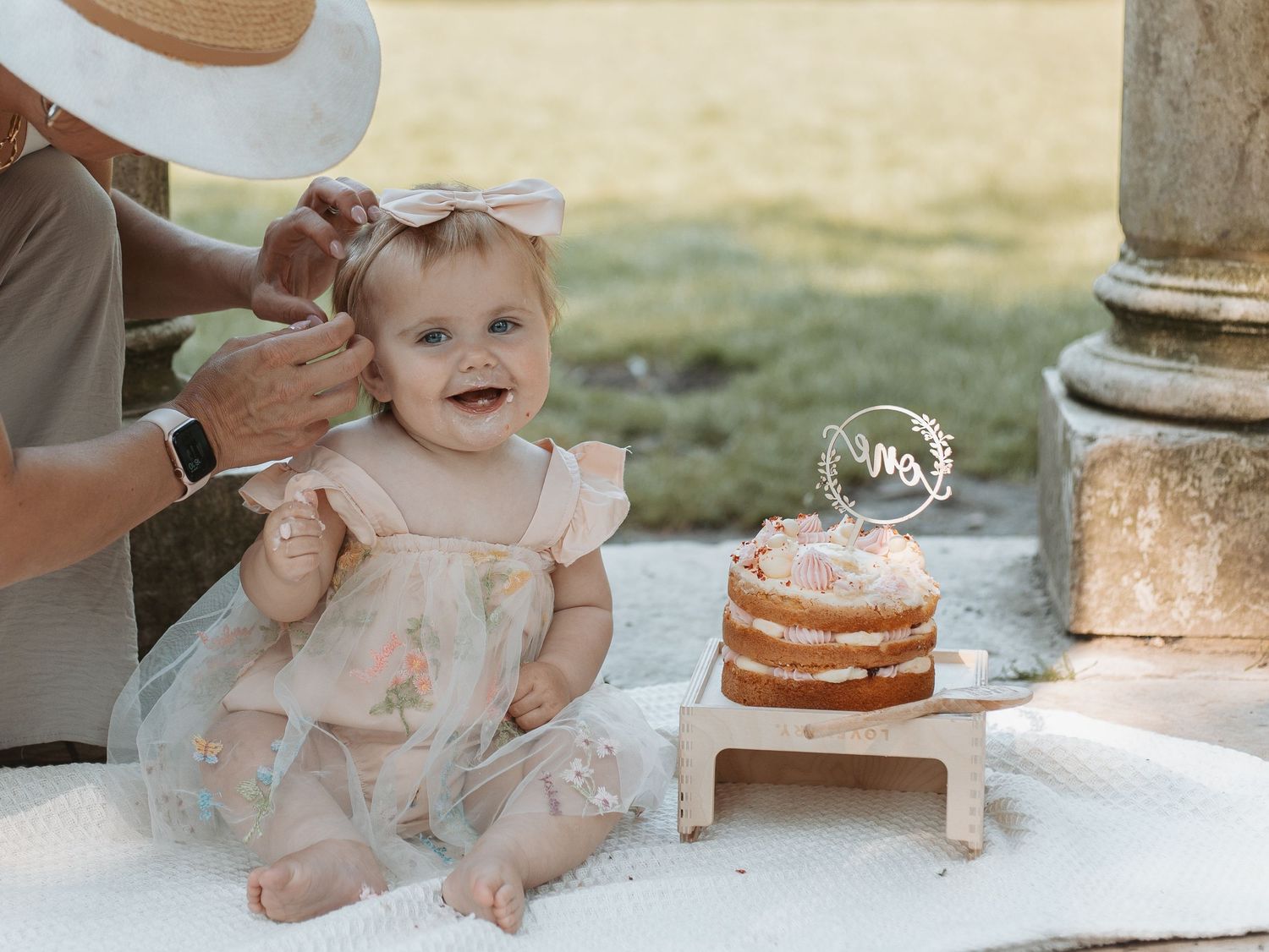 Baby playing with cake during outdoor photo session near stone columns.