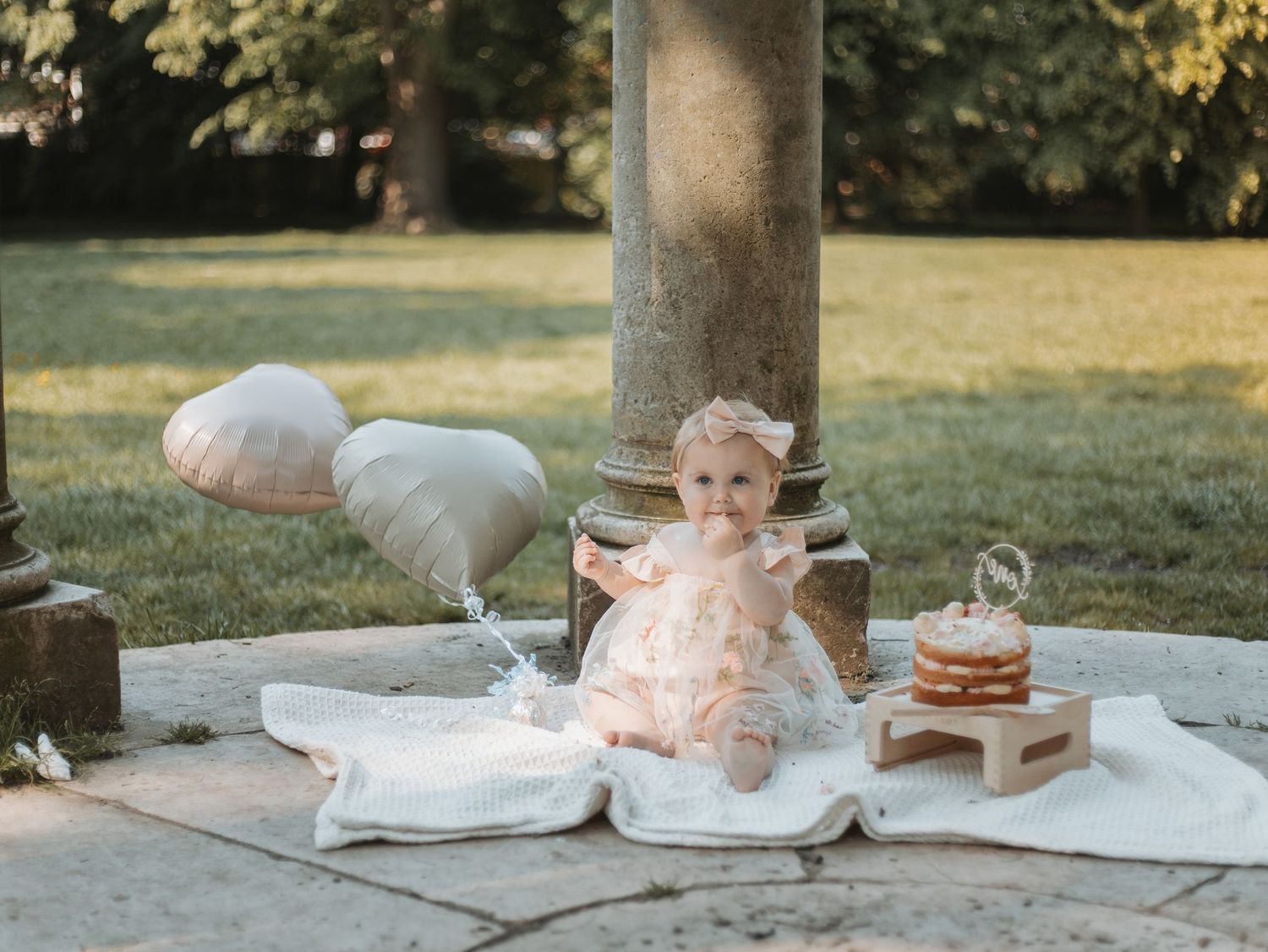 Outdoor cake smash photography setup with stone columns and natural lighting.
