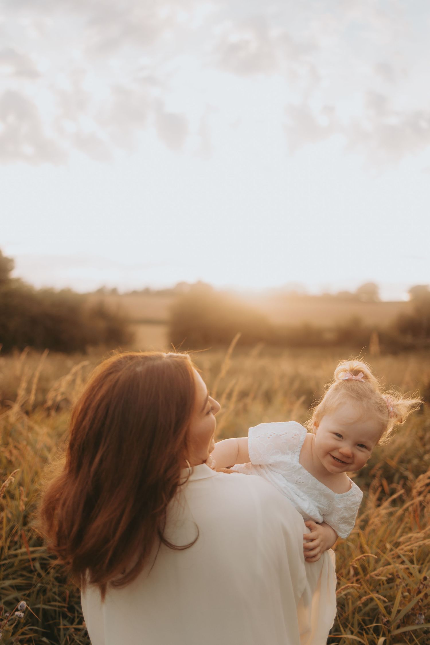 A joyful moment captured between parent and child in a sun-drenched field at golden hour.