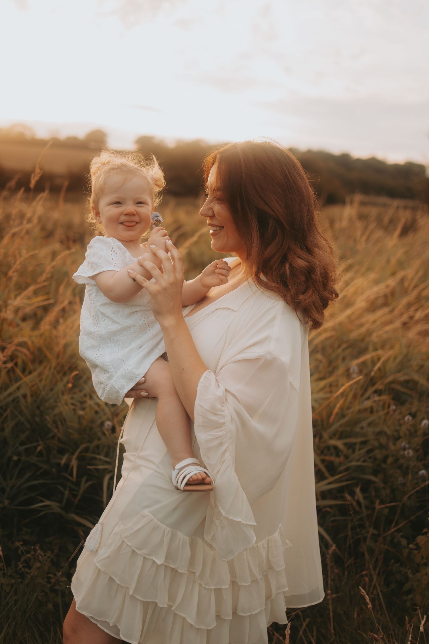 A tender moment between parent and child in a sun-drenched field at golden hour.