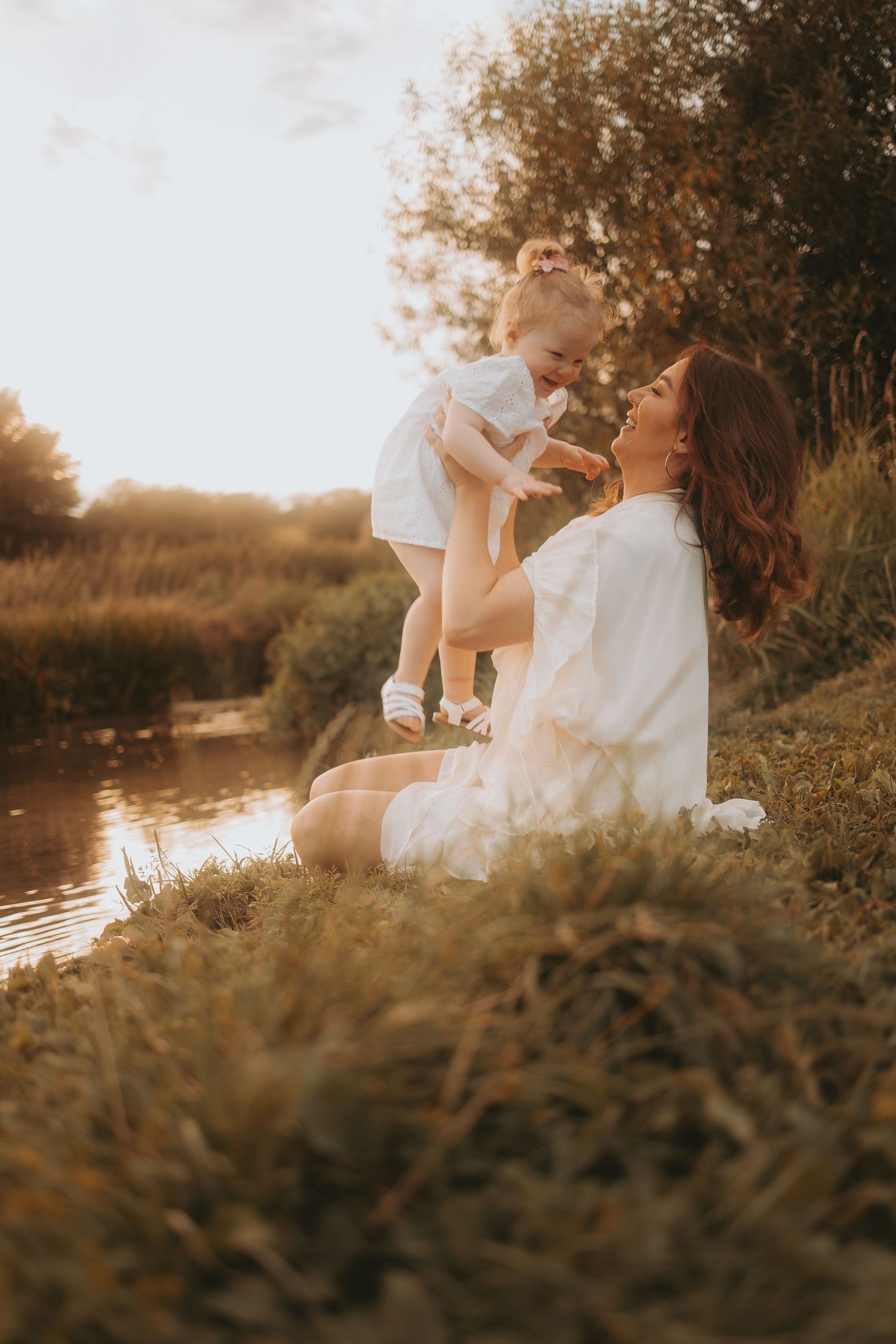 Artistic portrait session in a rustic outdoor setting with warm sunlight and tall grasses.