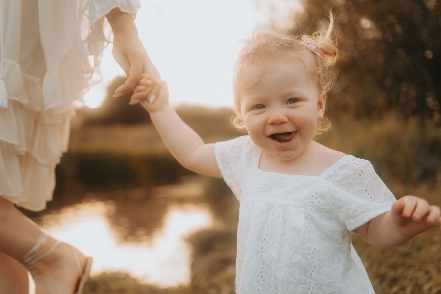 Candid moments captured in white outfits during a lakeside sunset photo session.