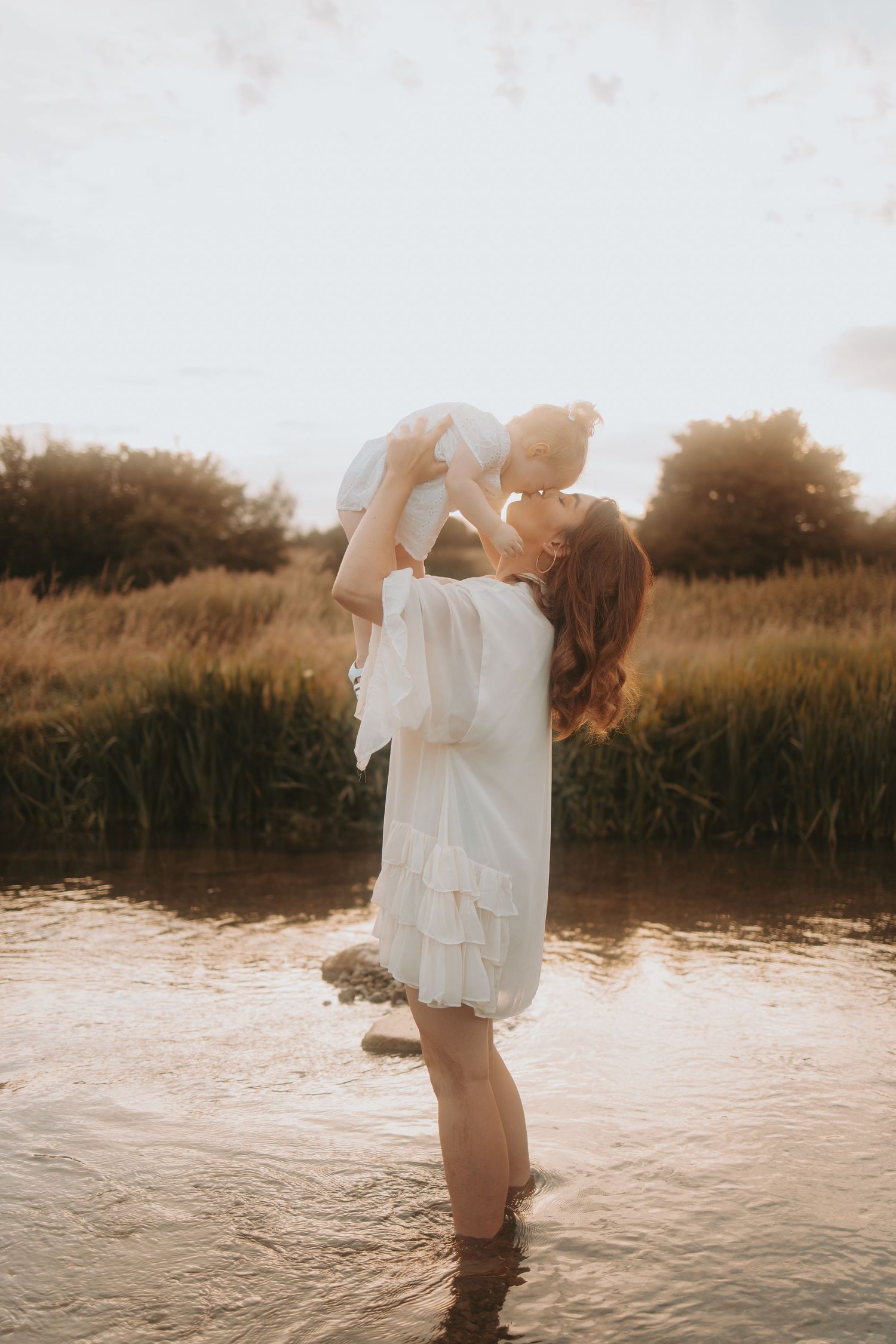 Artistic water photography session with white clothing and golden sunset reflections.
