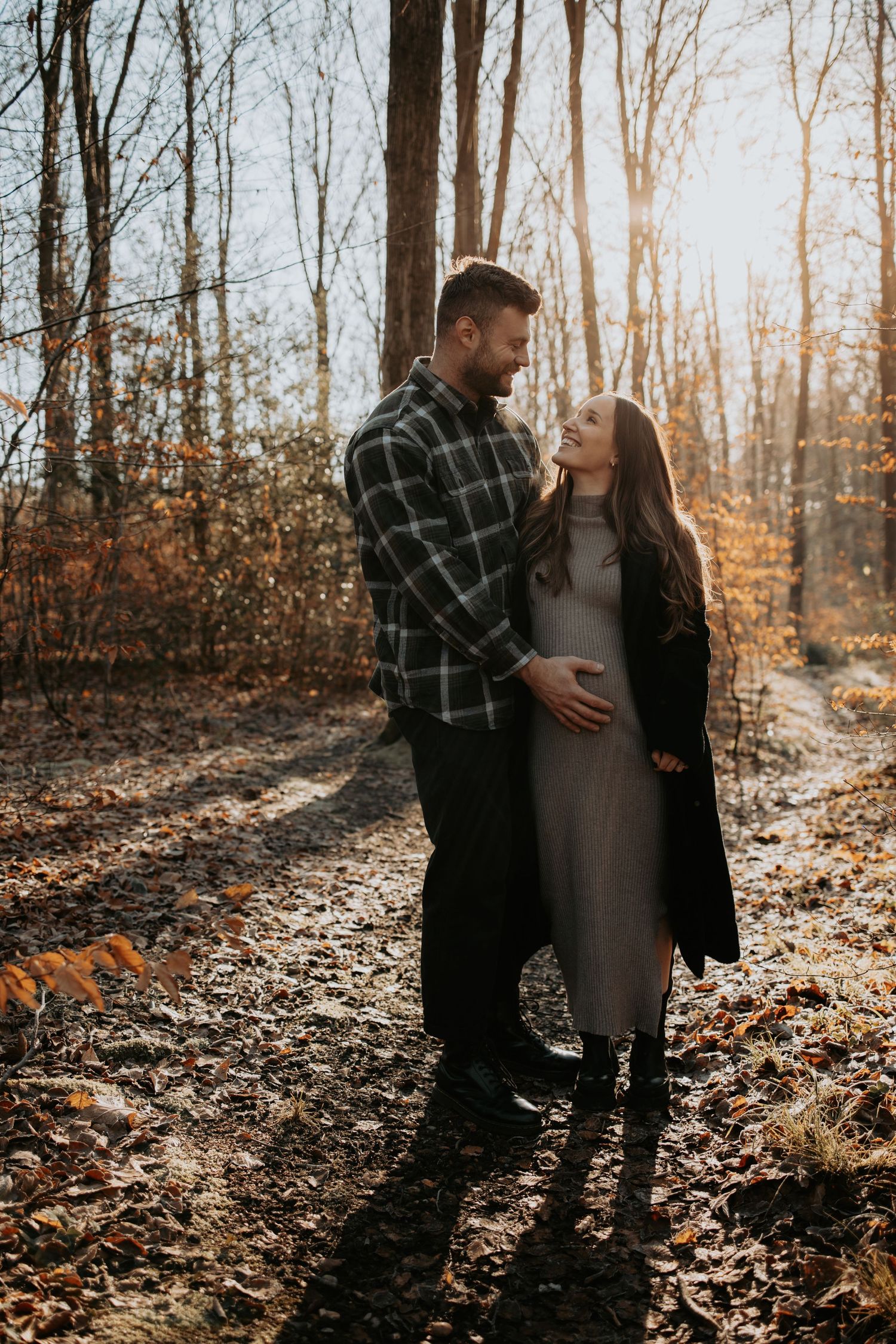 A romantic couple embracing in a forest during golden hour with fall foliage.