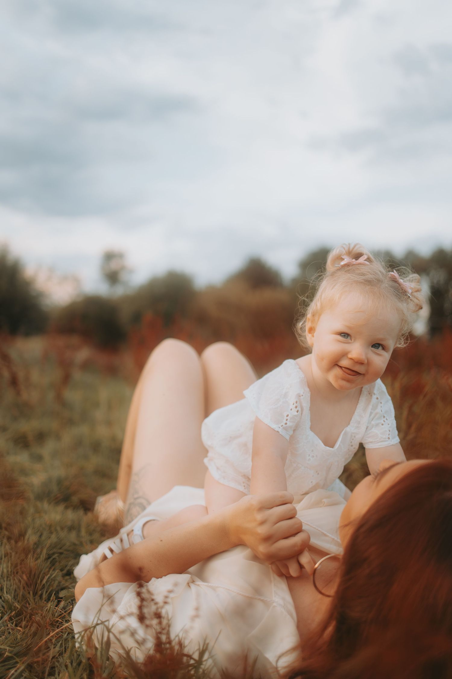 Sweet outdoor photography session in a natural field setting with warm lighting.