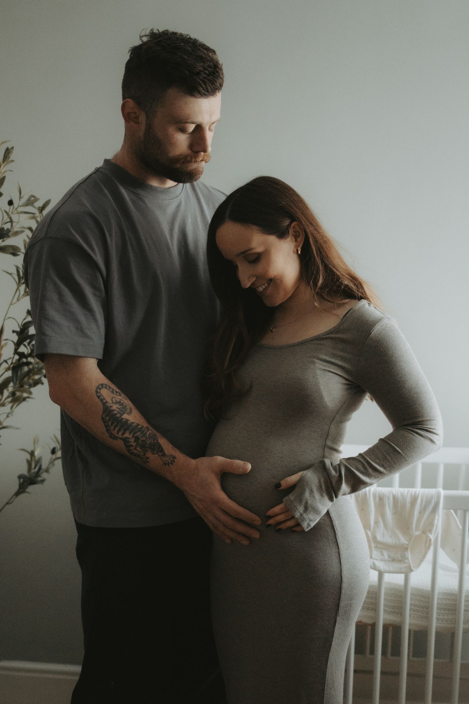 A tender maternity moment captured in a minimalist nursery setting.