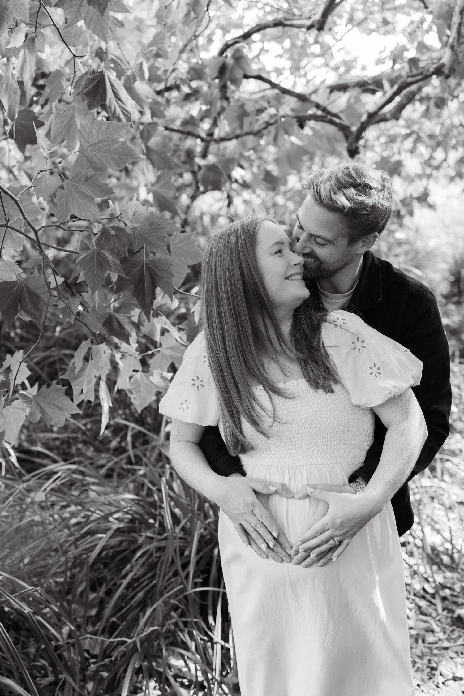Black and white photo of tender embrace in a garden setting.