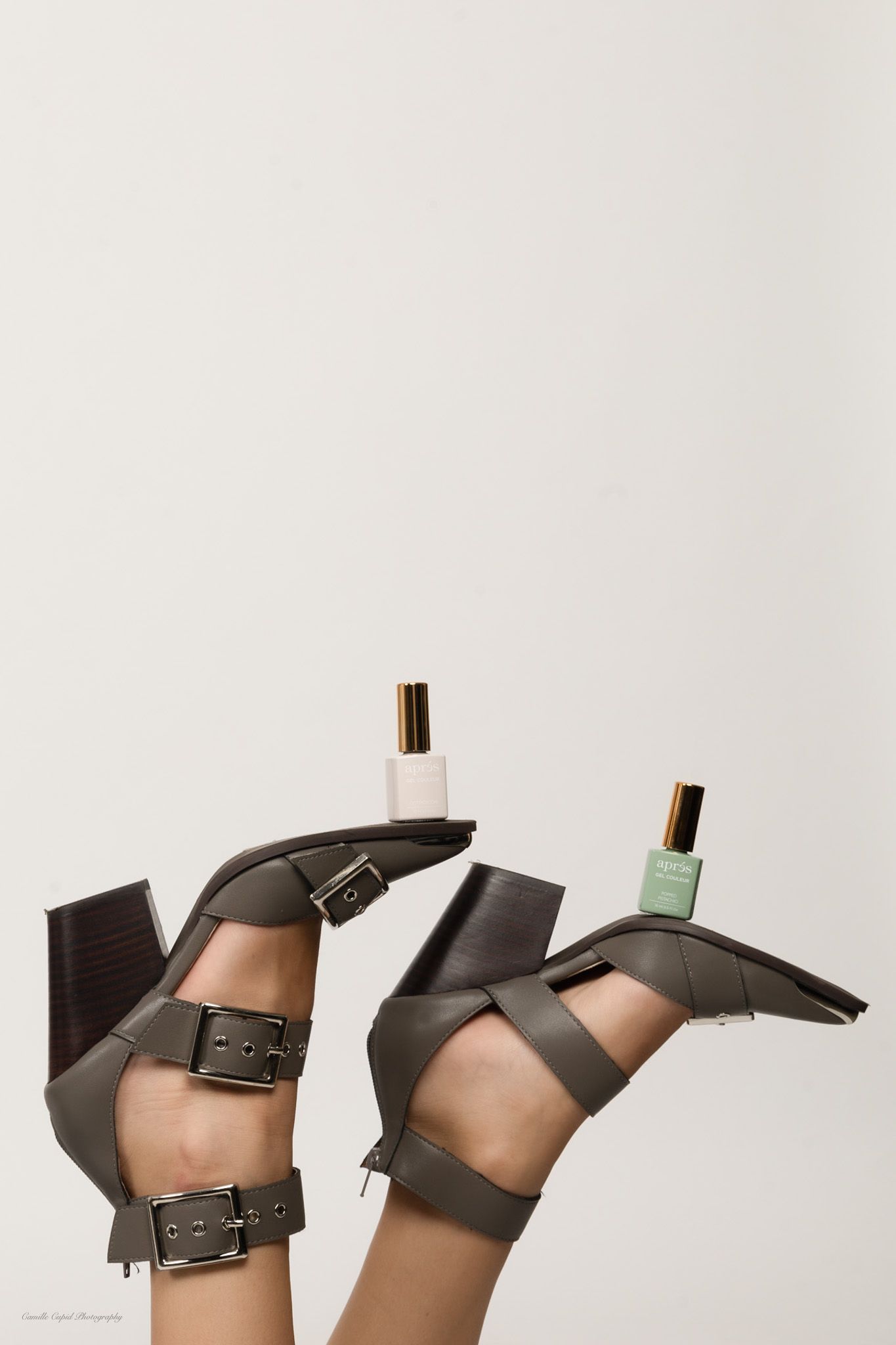 Creative product flatlay featuring nail polish bottles balanced on gray heels, studio personal branding by Camille Cupid Photography