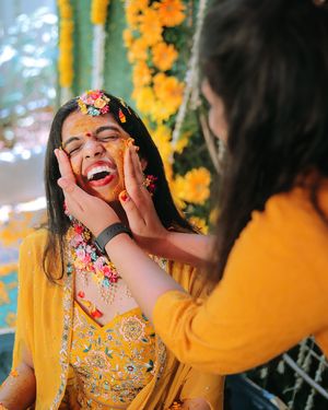 Playful moment during Haldi ceremony with yellow outfits and floral decorations.