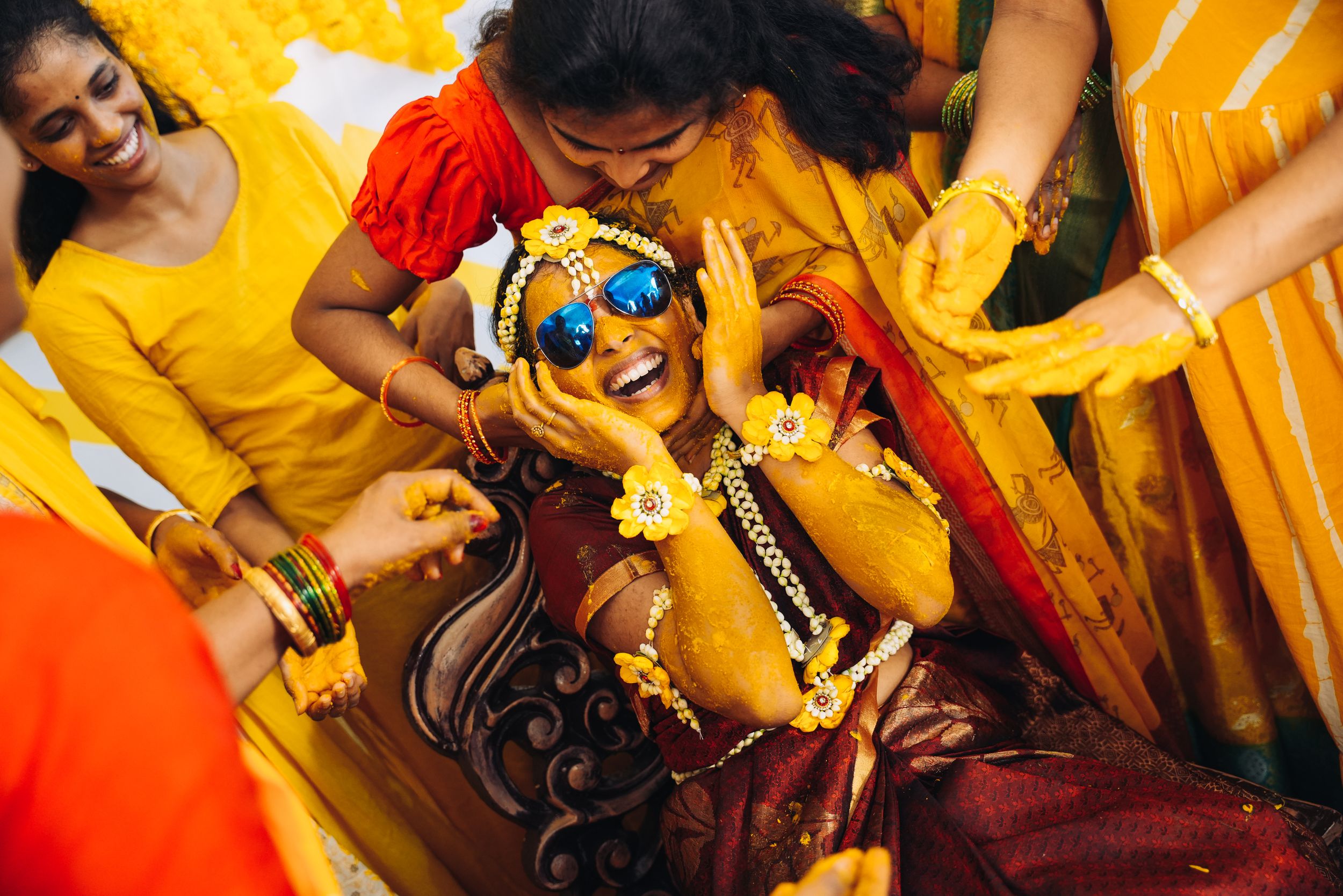 Festive Indian pre-wedding celebration with participants in yellow and red traditional attire.