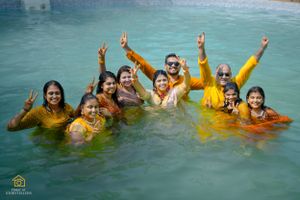 Group of friends celebrating in a swimming pool with yellow outfits and joyful expressions.