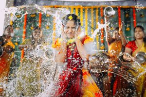 Joyful celebration with water splashing during traditional Indian ceremony with marigold decorations.