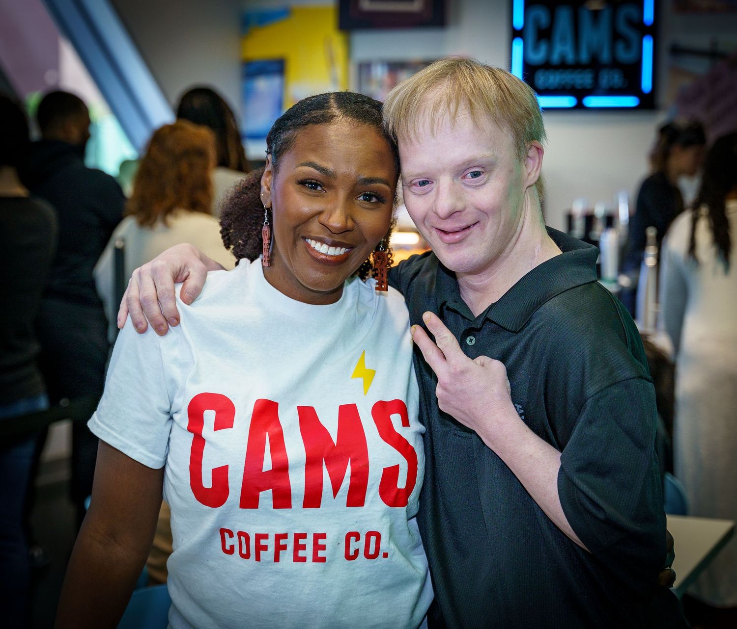 Staff members at CAMS Coffee Co pose together in front of the company signage.