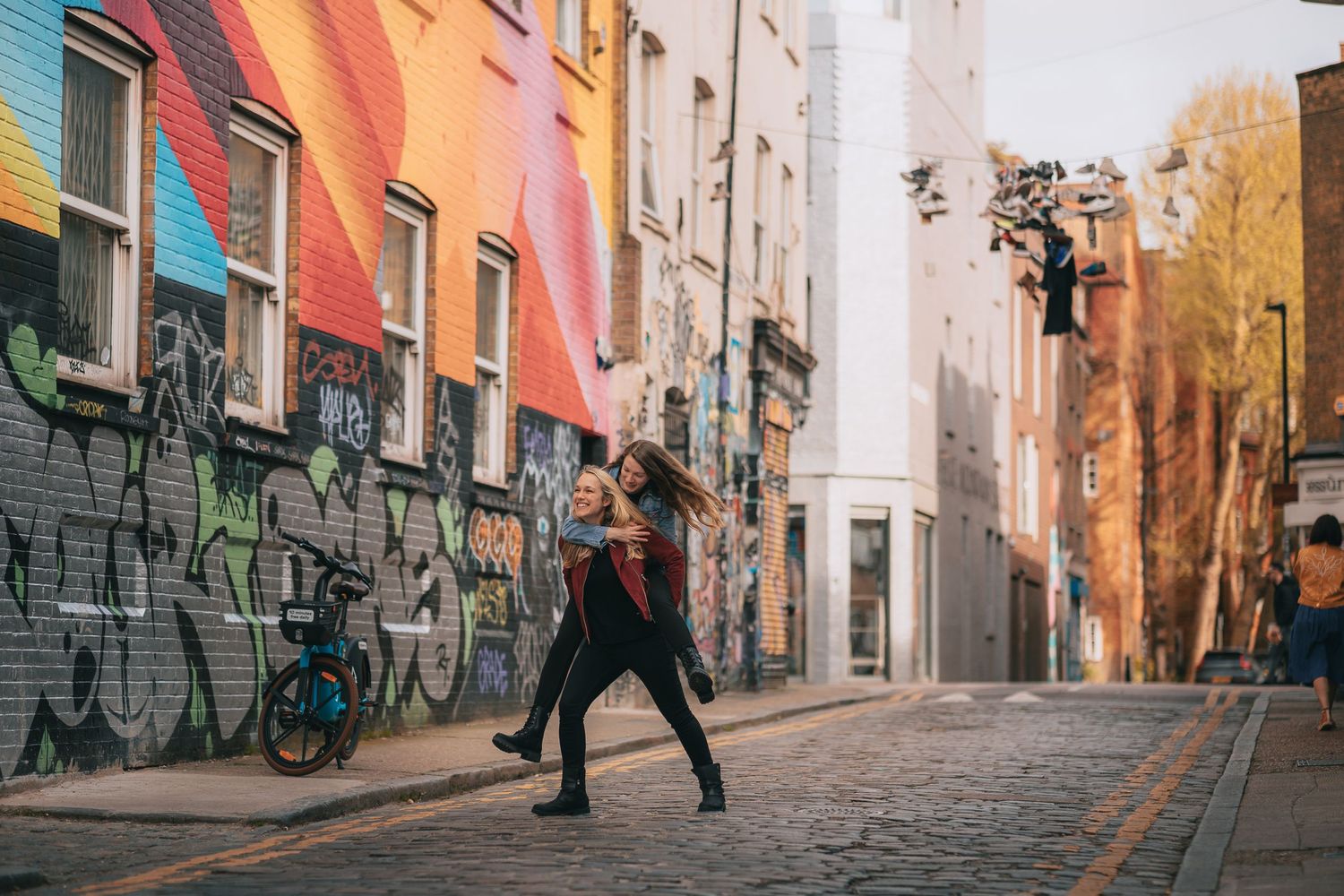 Person walking past colorful graffiti walls in an urban alley.