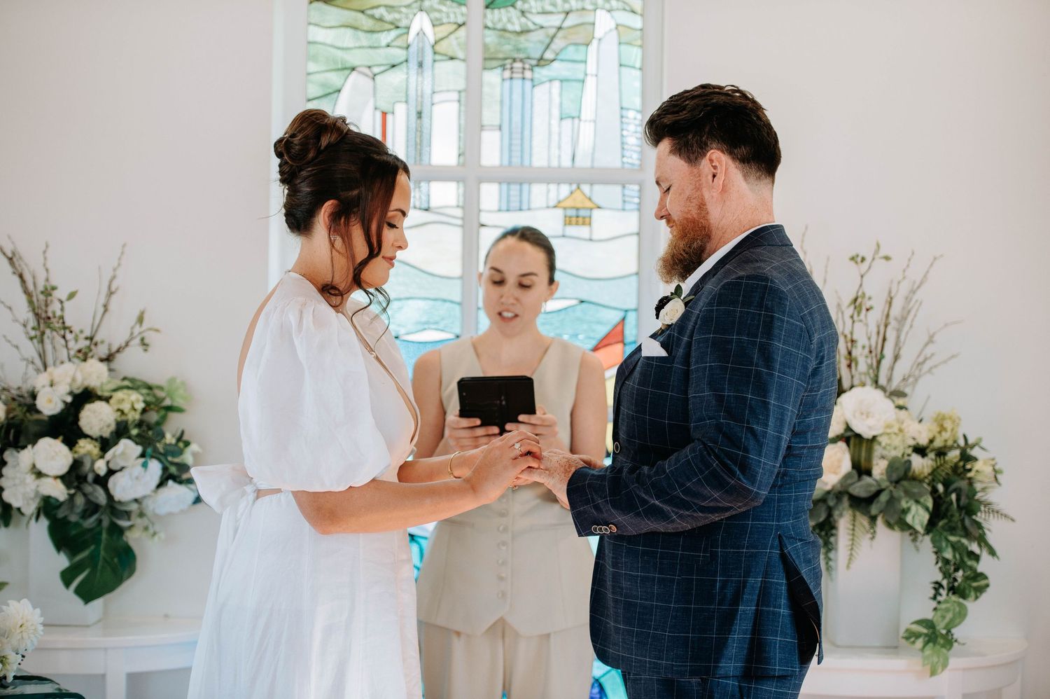 Indoor wedding ceremony with couple exchanging vows in front of officiant.