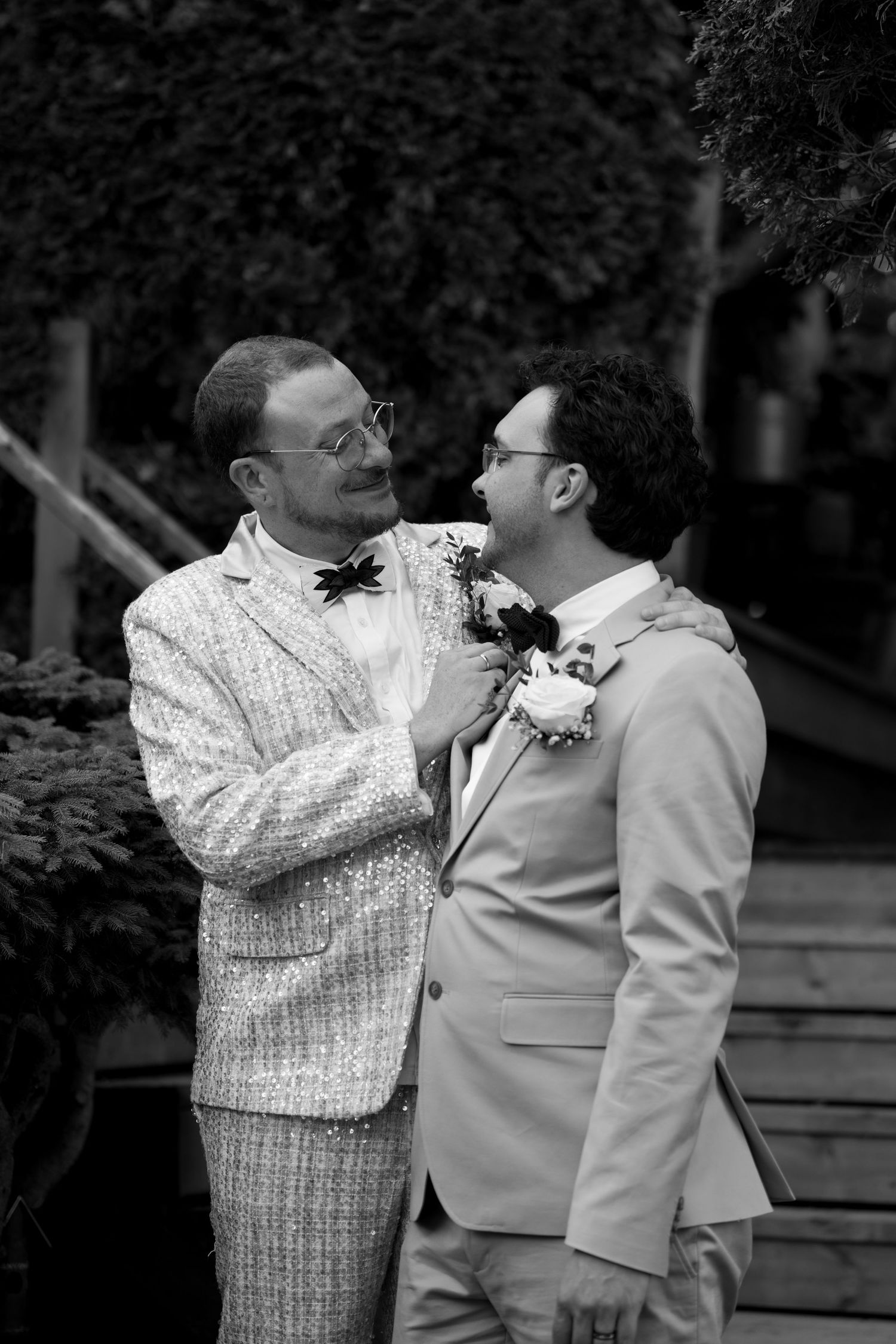 A black and white portrait of a couple in wedding attire sharing an intimate moment.