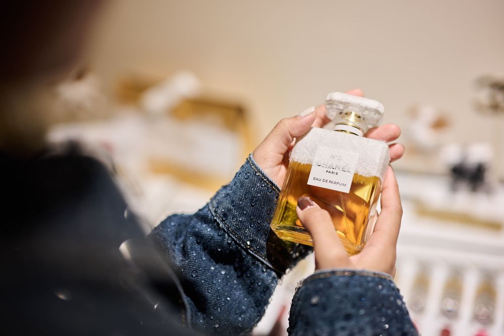 Person holding a bottle of Chanel perfume at a fragrance counter.
