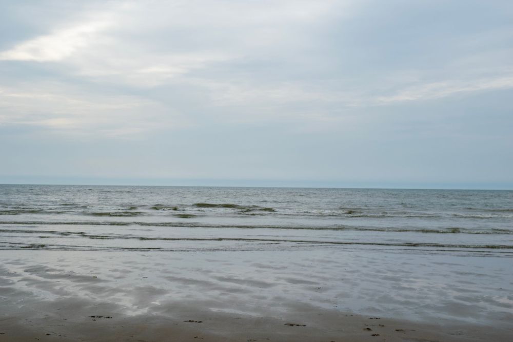 Serene ocean view with gentle waves under cloudy grey skies.