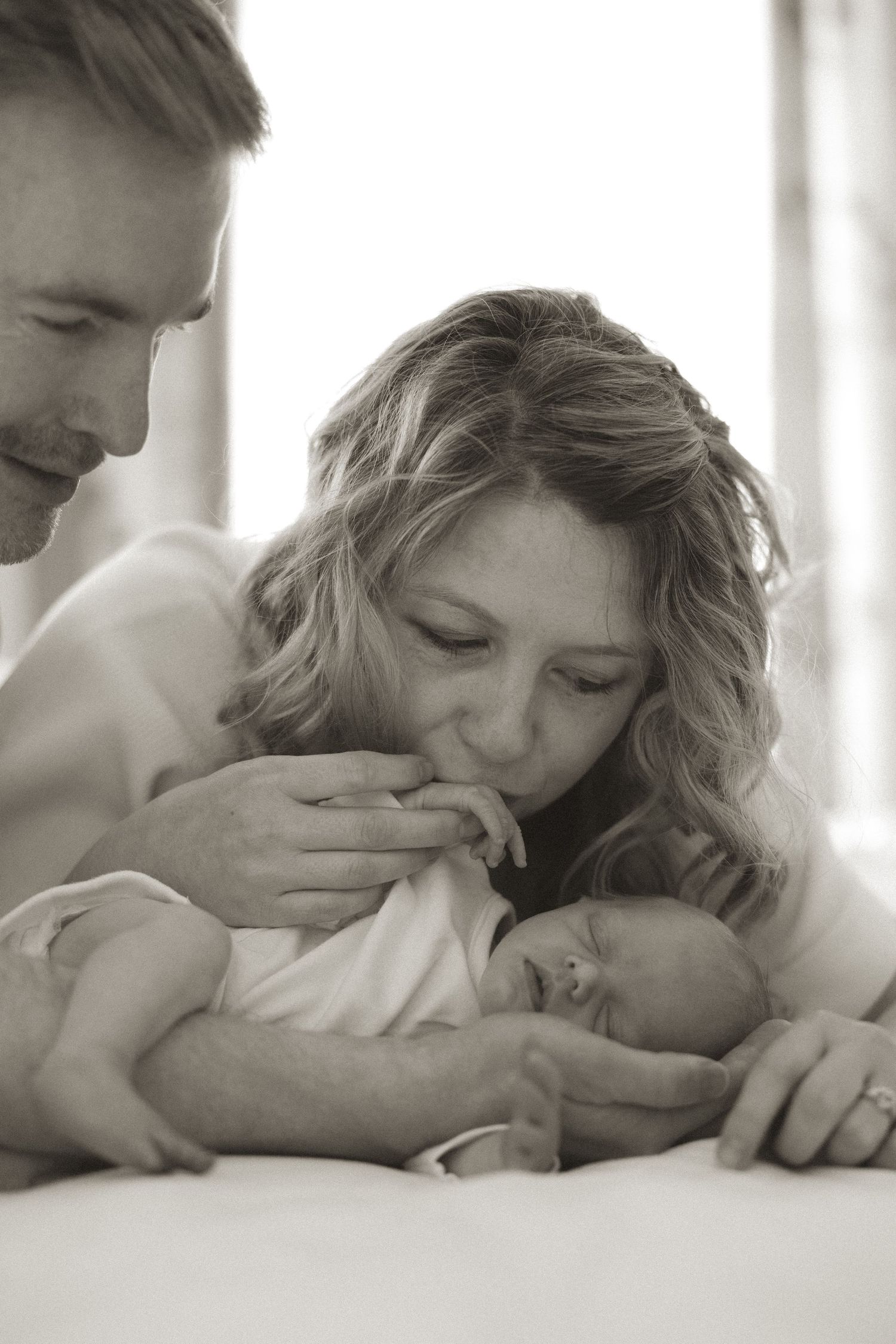 Intimate black and white portrait in window light showing tender moment.