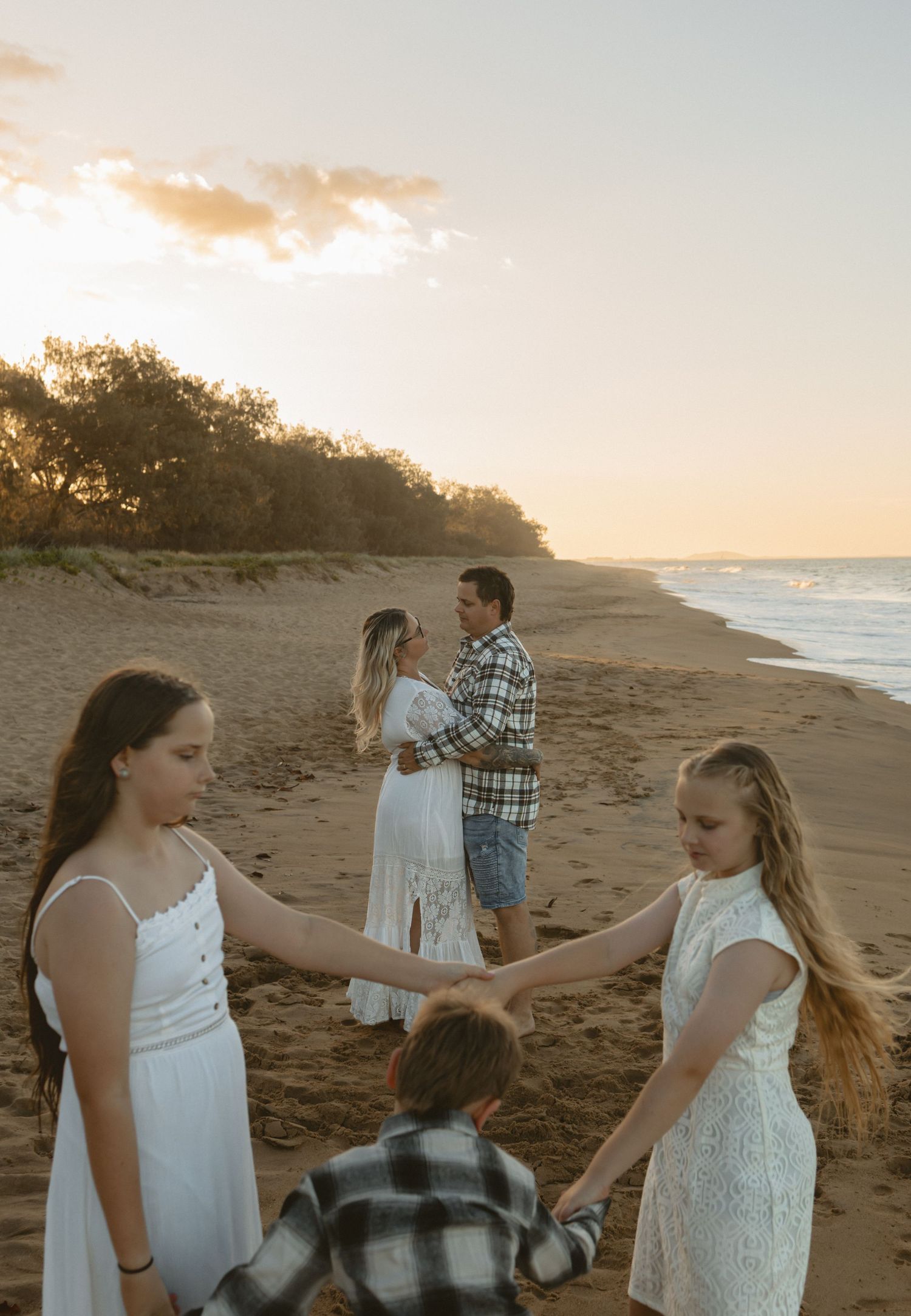 A sunset beach scene with families enjoying time together on the sandy shore at golden hour.