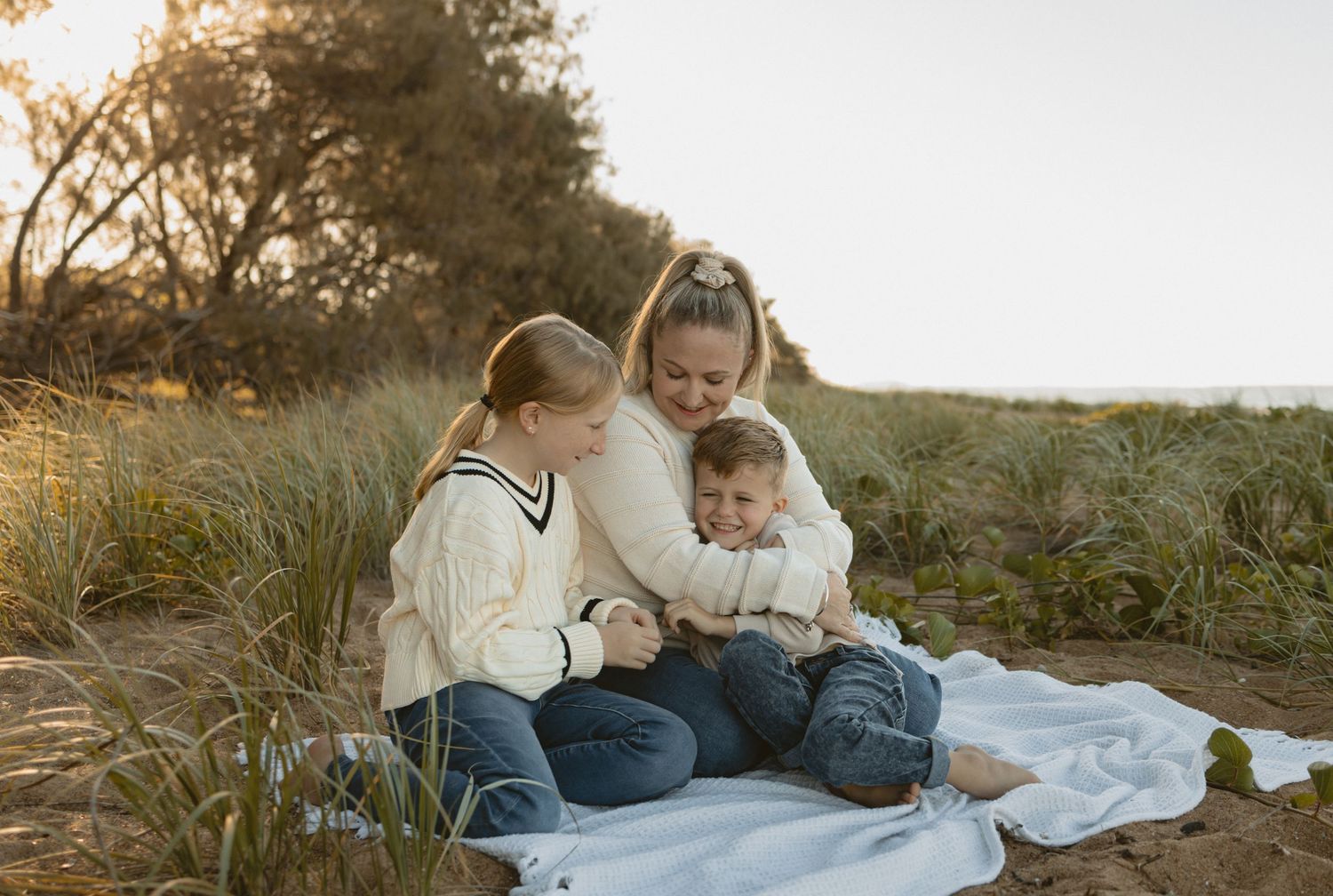 Couple in white outfits sitting together outdoors at sunset in a romantic field setting.