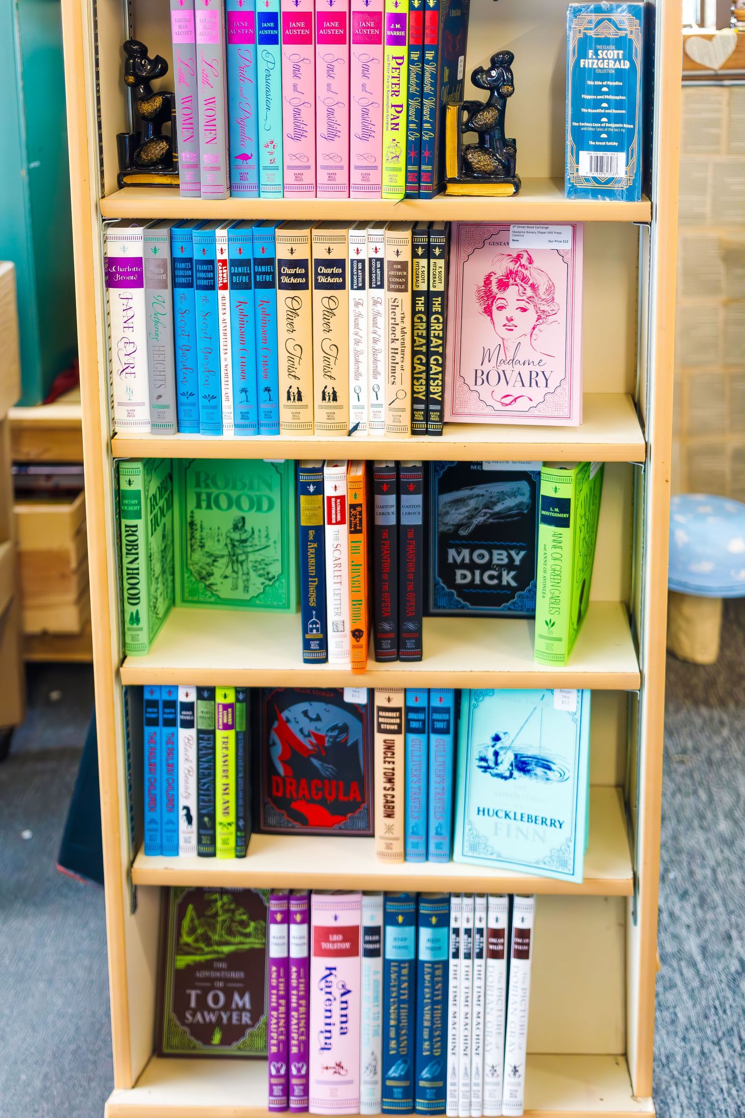 Colorful bookshelf displaying various book spines in rainbow order with decorative bookends.