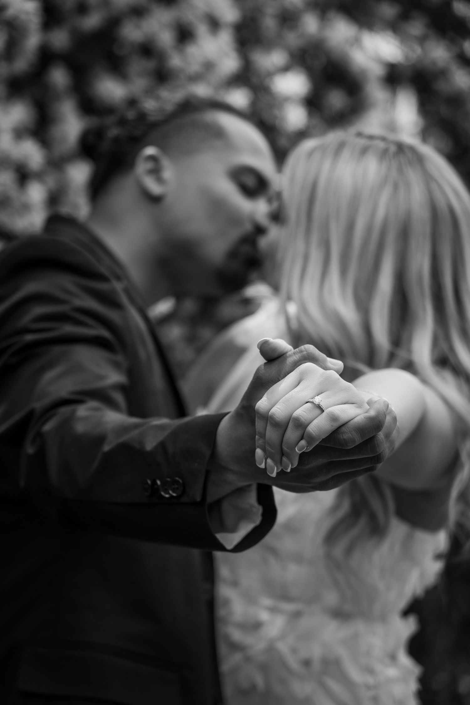 A couple shares an intimate black and white portrait while smiling at each other.