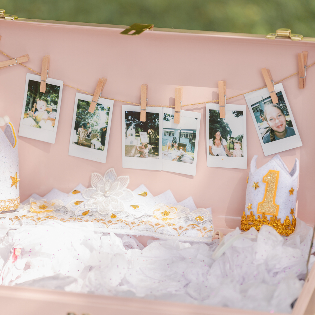 Vintage photos hung on clothespins against a pink backdrop with party decorations.