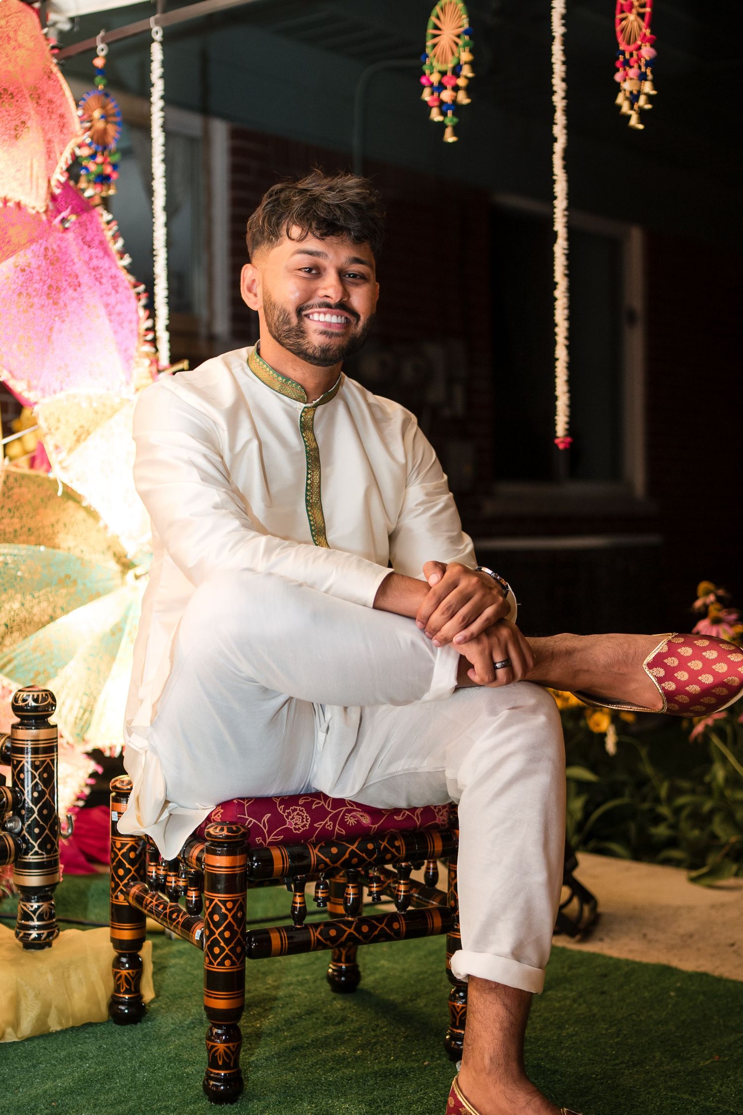 Wedding portraits on decorated outdoor set with hanging lights and traditional cultural elements.