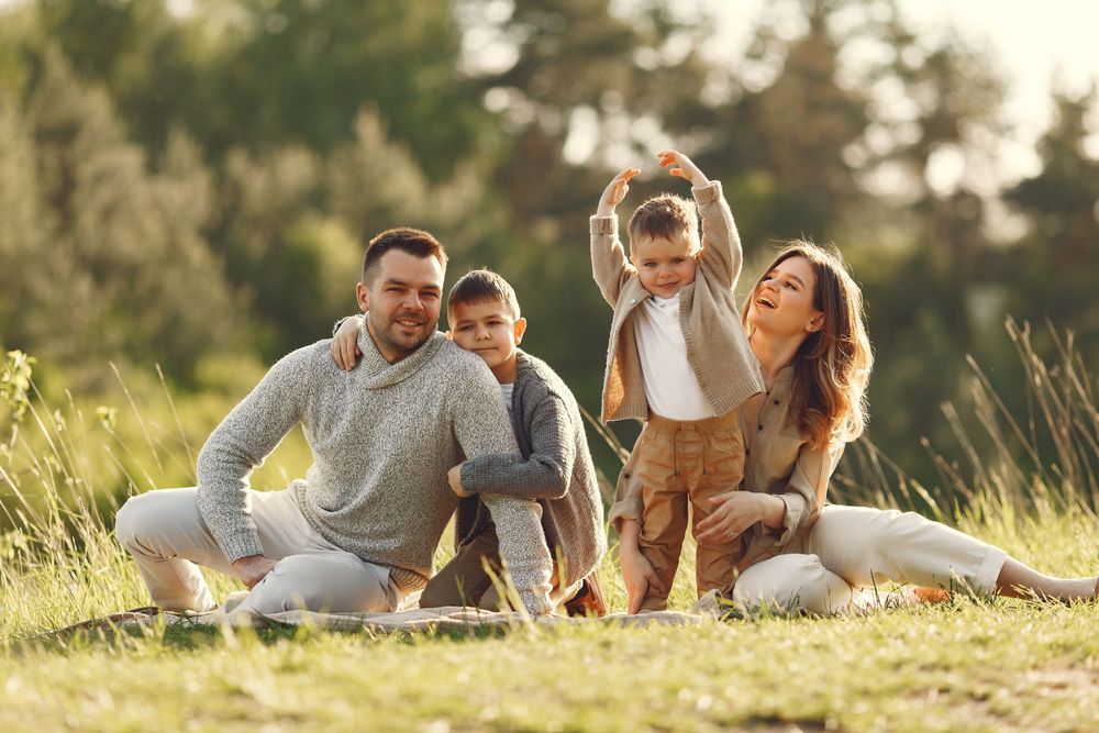 Happy family enjoying outdoor time together in sunlit meadow at golden hour.