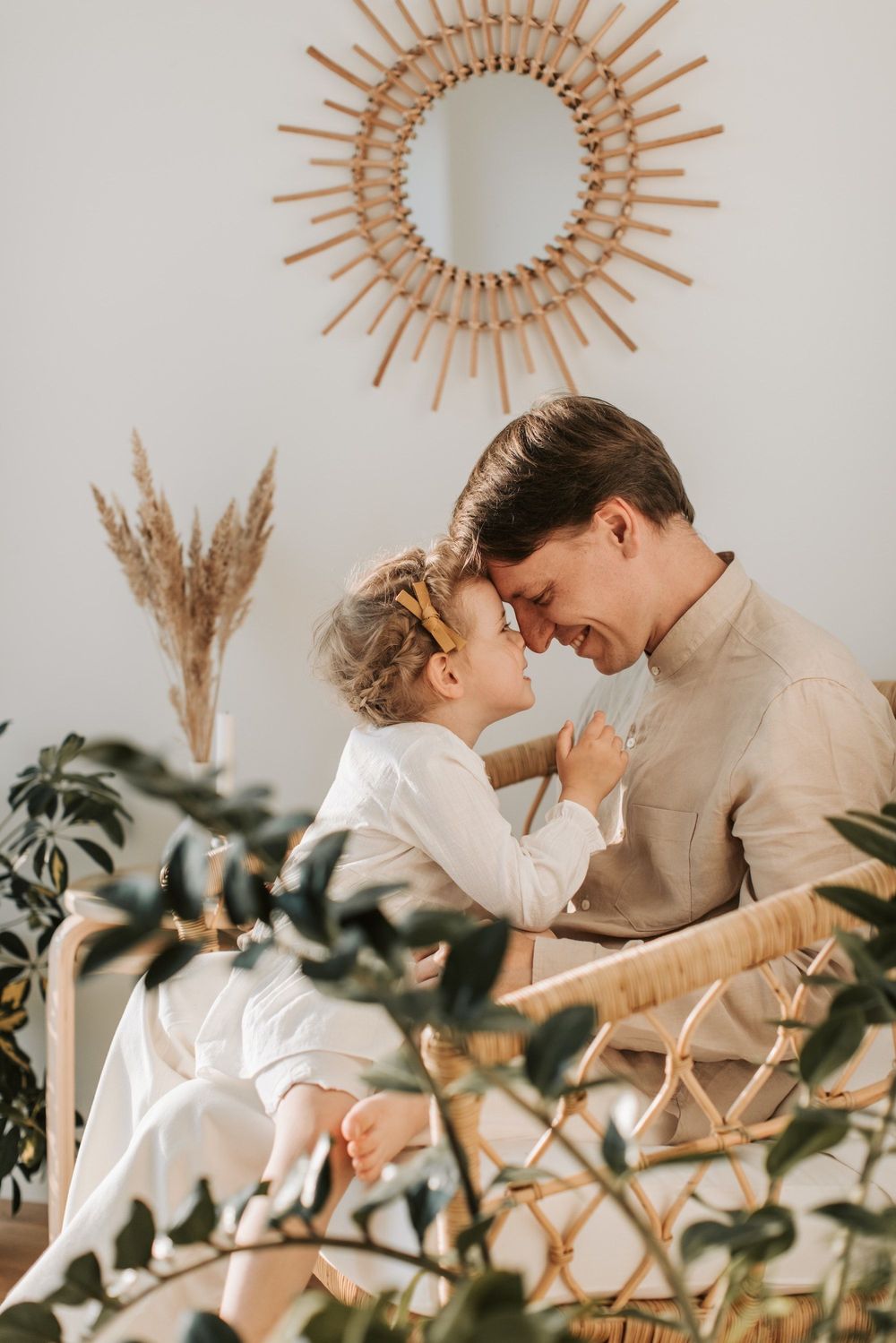 A touching family moment under a rattan sunburst mirror with pampas grass decor.