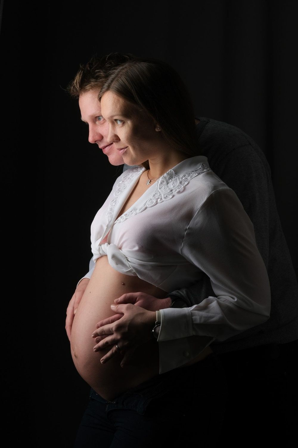 Intimno nosečniško fotografiranje para v Krškem – čustven studijski portret nosečnice in partnerja.