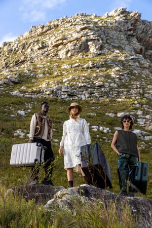 Adventurous group standing with luggage on rocky mountain terrain.