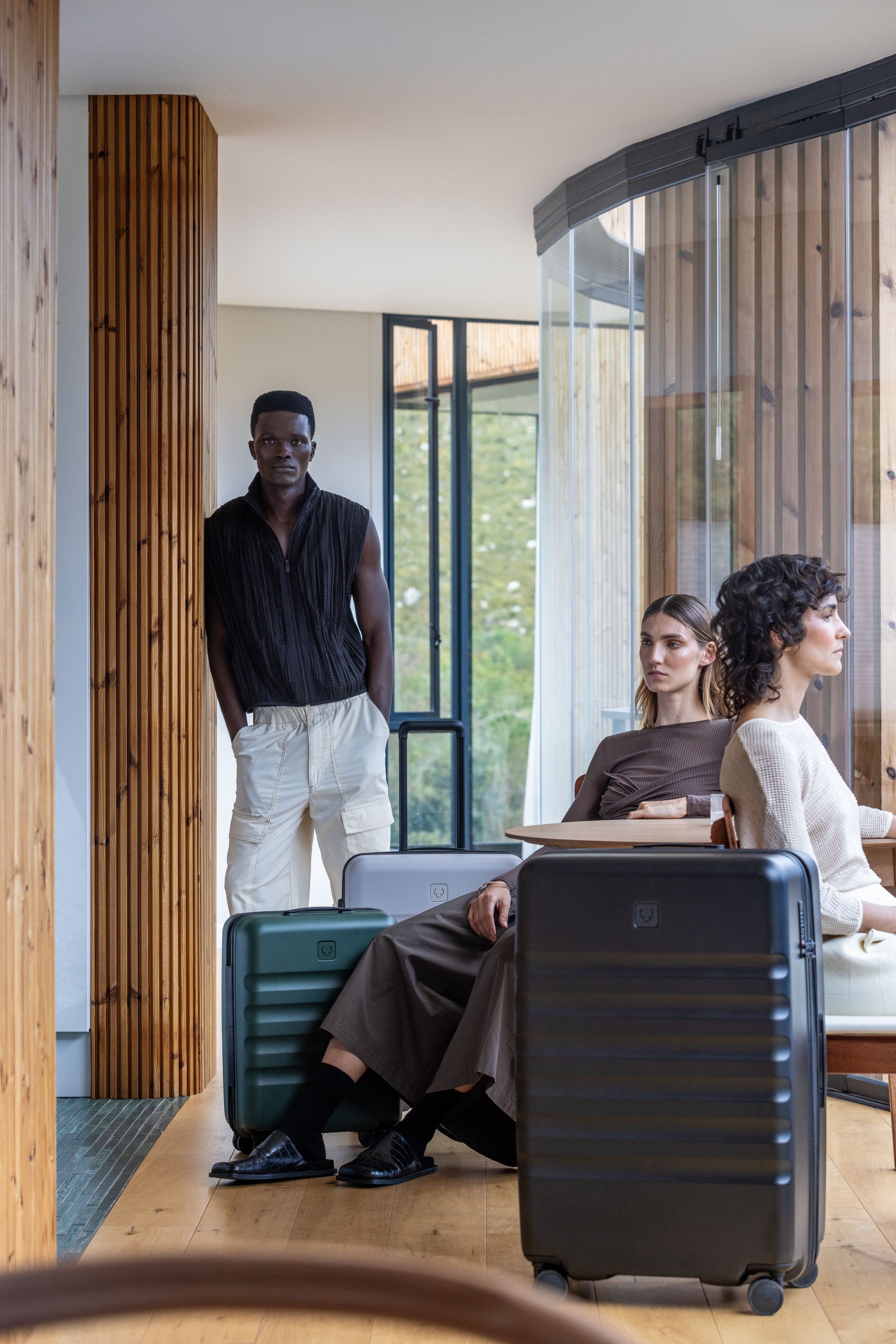 Modern hotel lounge area with wooden decor and guests with luggage.