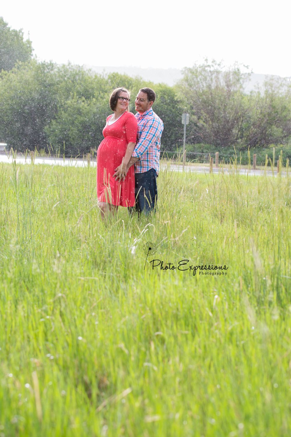 Romantic portrait in tall grass field with red dress and plaid shirt.