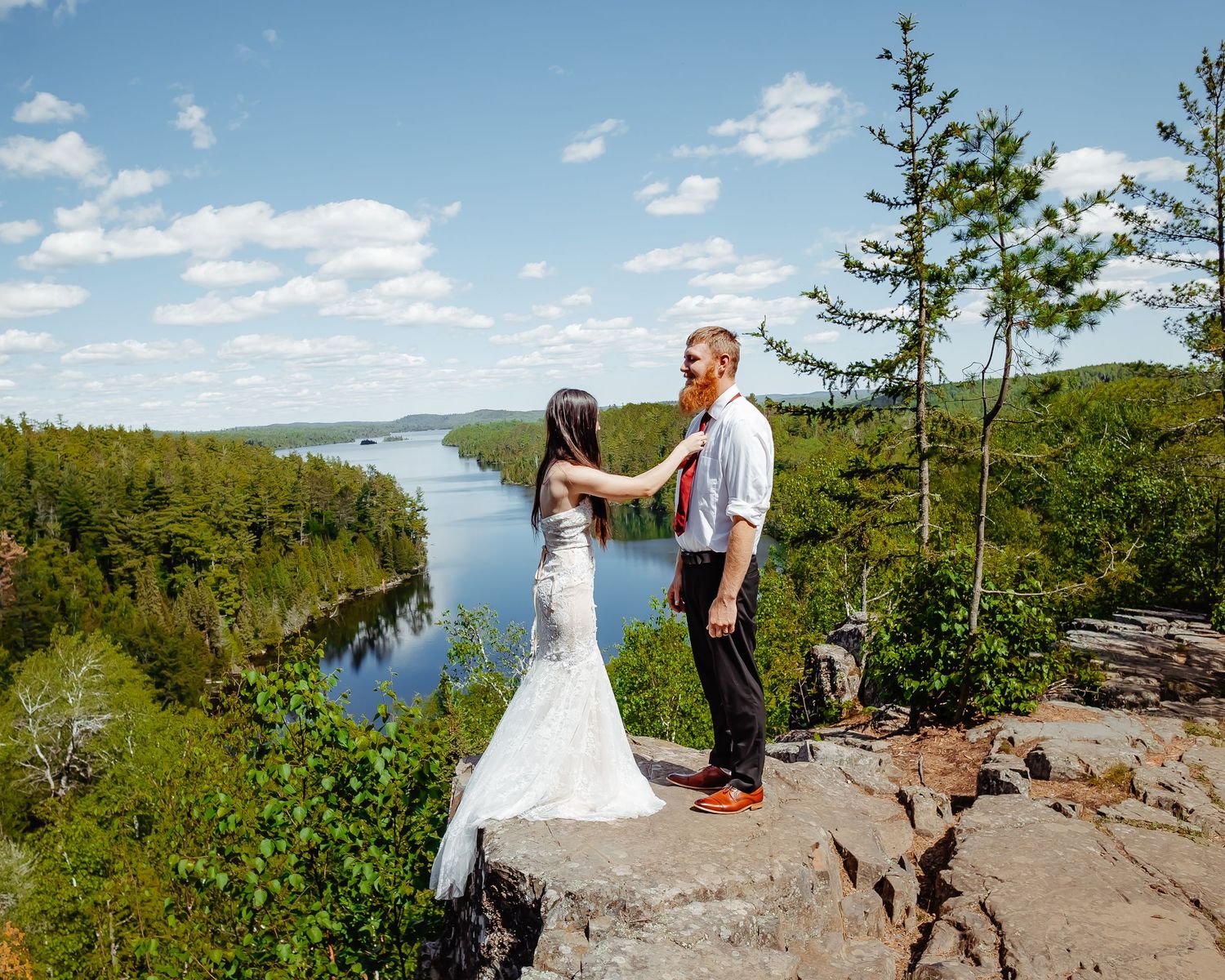 A romantic moment captured on a scenic cliff edge with a meandering river and forest landscape below.