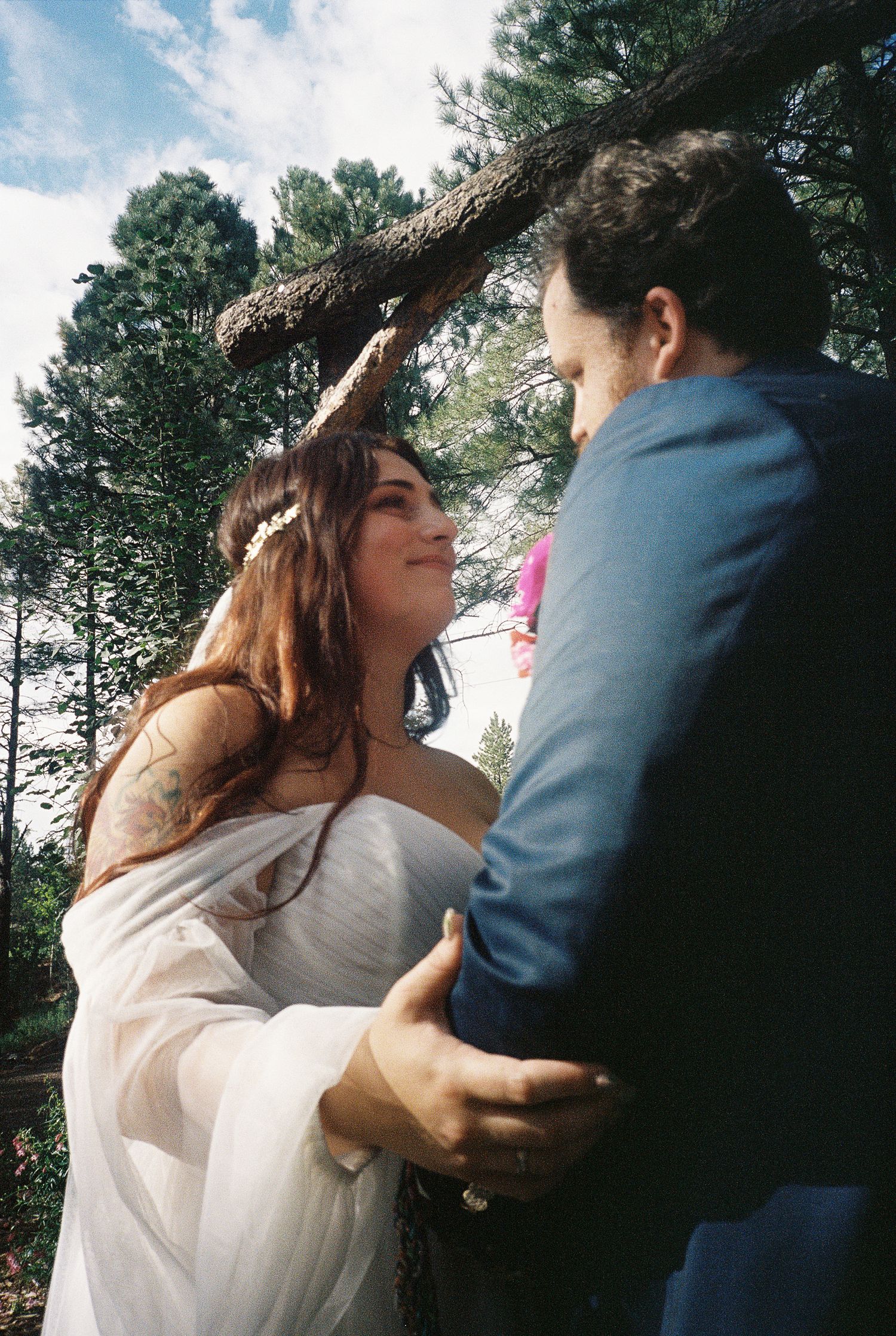 Romantic outdoor wedding moment under pine trees.