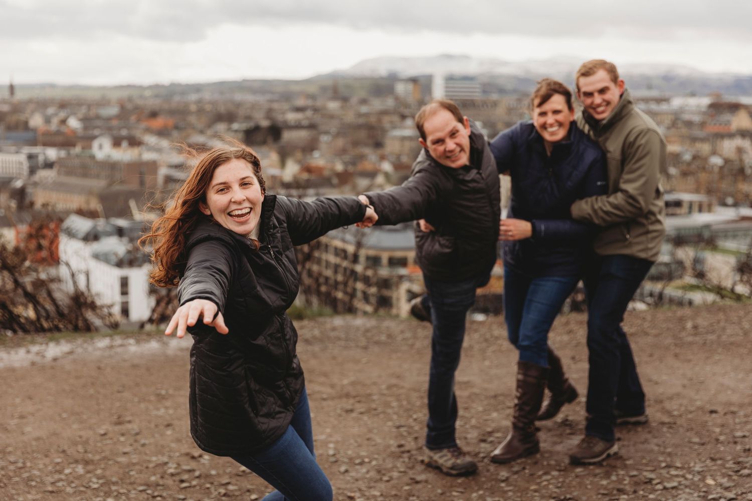 Friends having fun posing on a hilltop overlooking a city landscape.