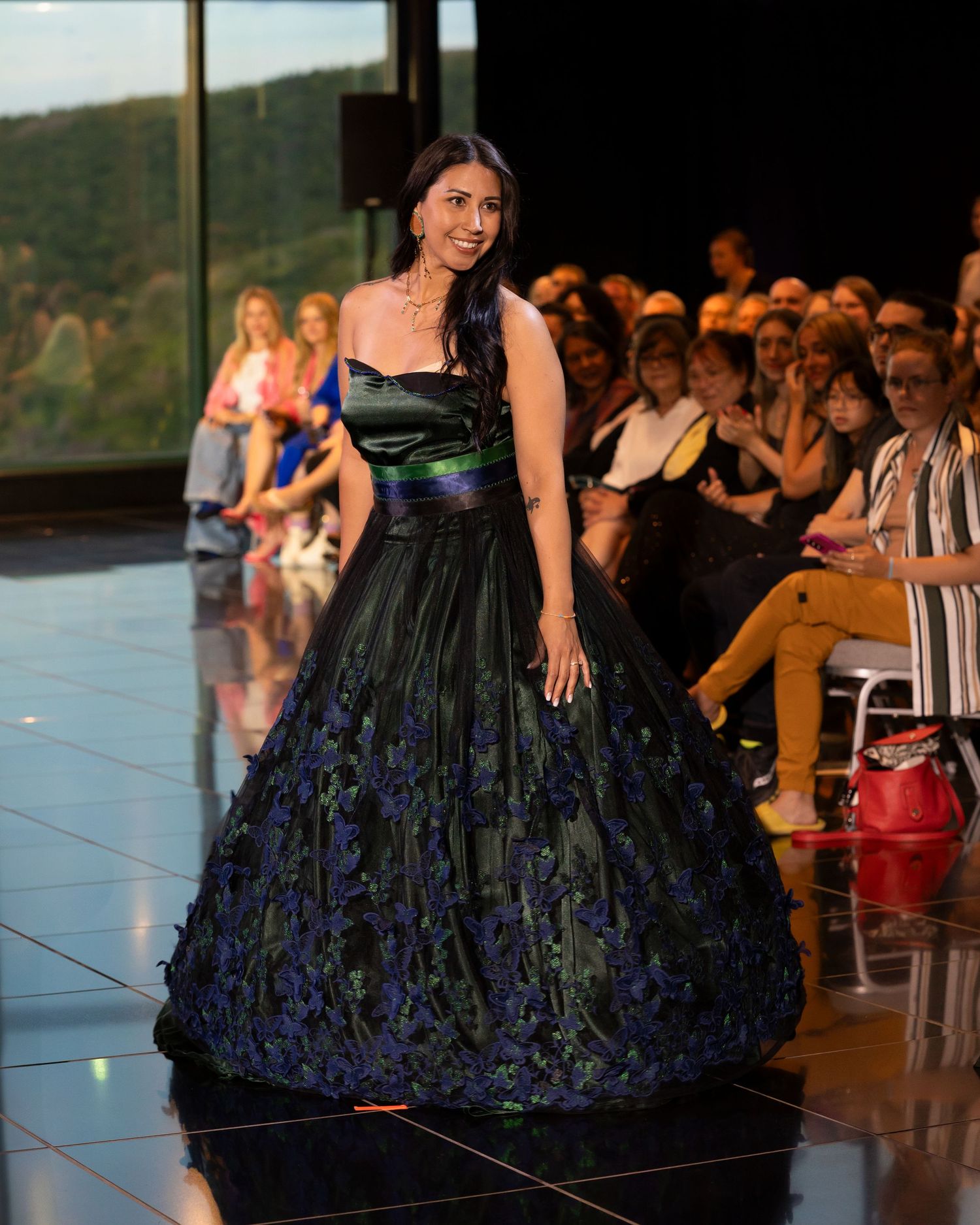 A model walks the runway in an elegant black and navy floral ballgown with a fitted bodice during a fashion show.