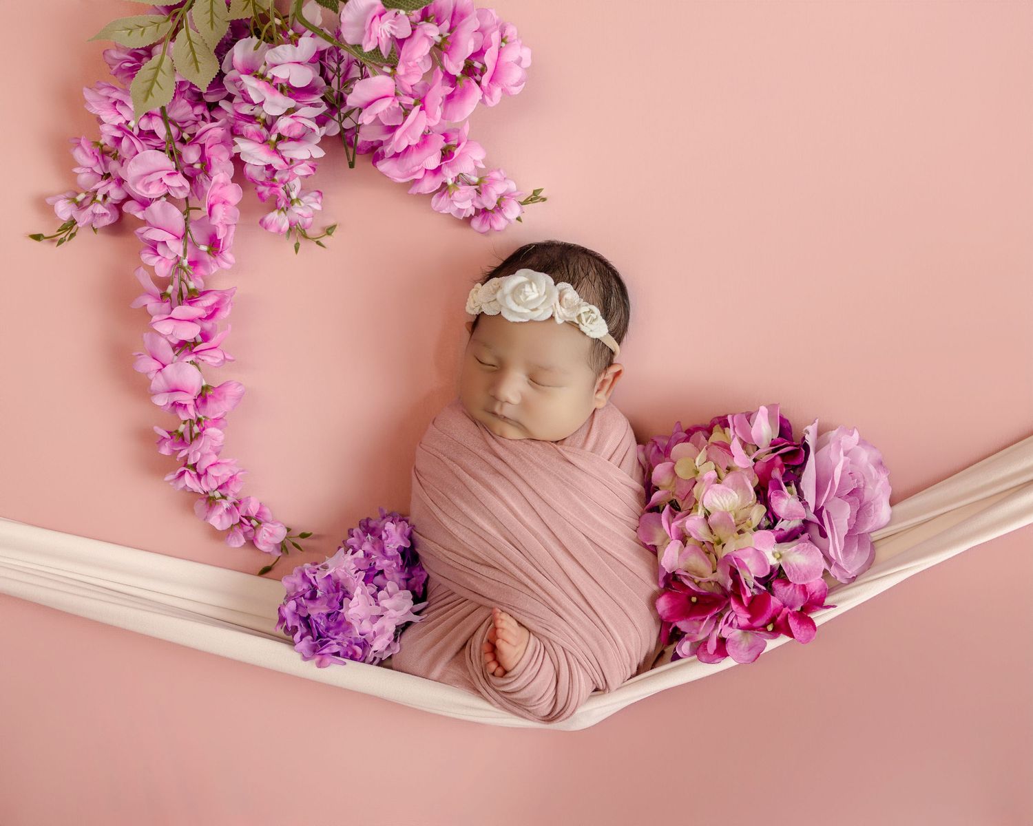 Peaceful newborn baby sleeping on green pillow wearing white knit hat.