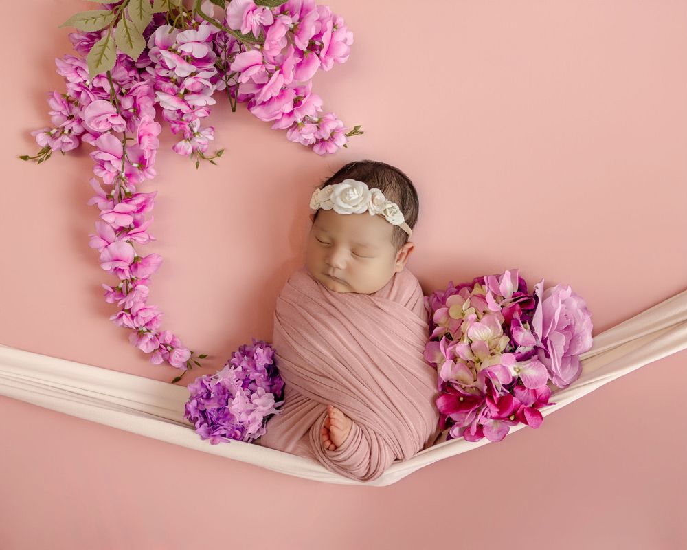 Peaceful newborn baby sleeping on green pillow wearing white knit hat.