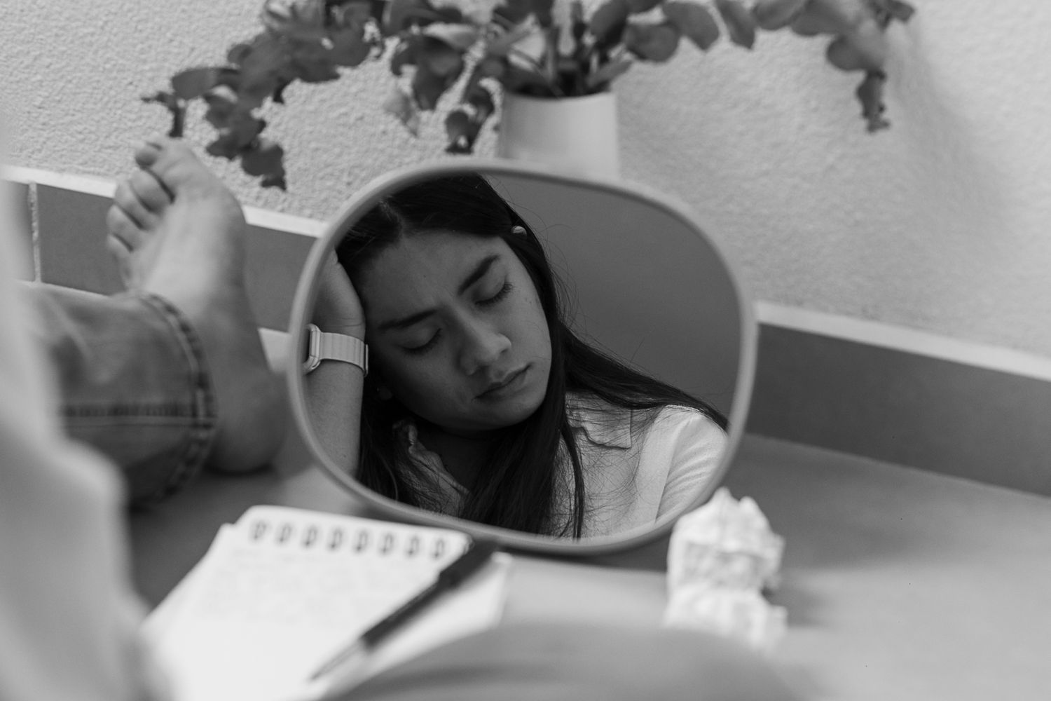 A small mirror reflects a study scene with notebooks and indoor plants.
