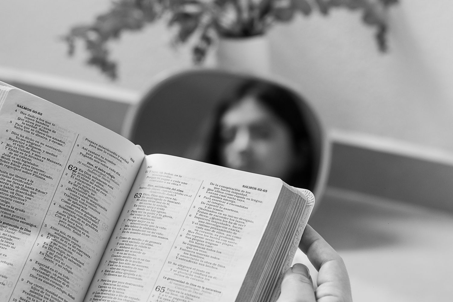 Black and white image showing someone reading a document at a desk with scattered papers.