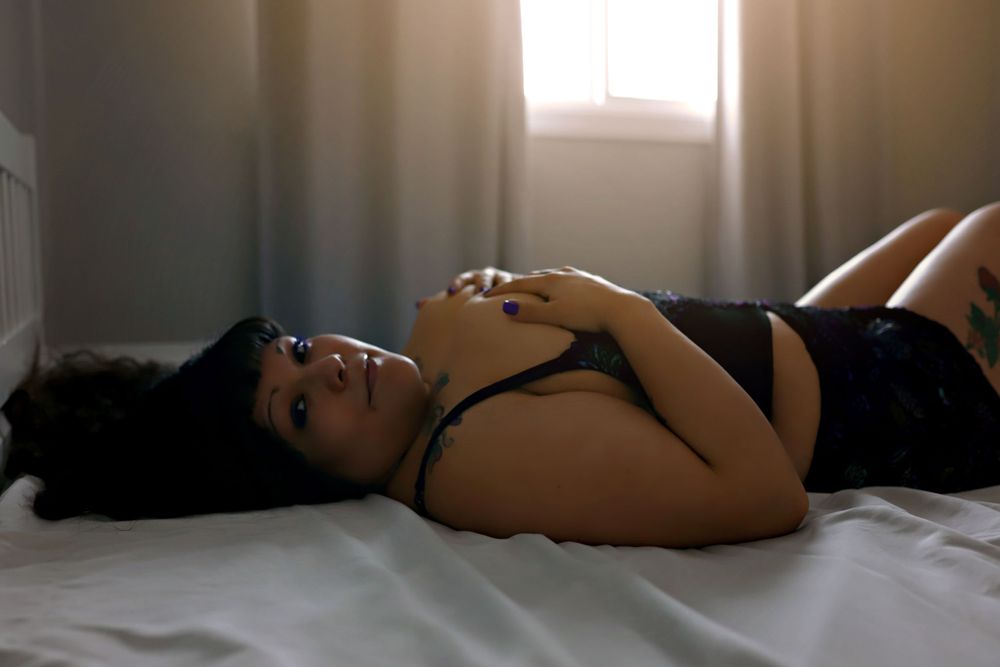 Sensual boudoir photography with dramatic shadows on white linens.