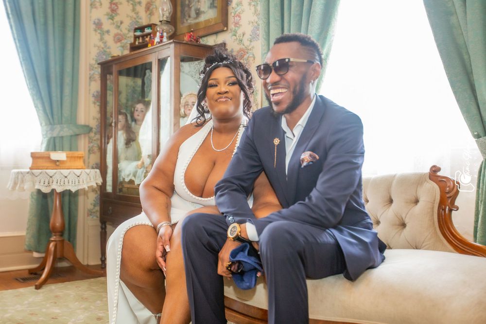 Candid moment of well-dressed couple sharing laughter on antique furniture.