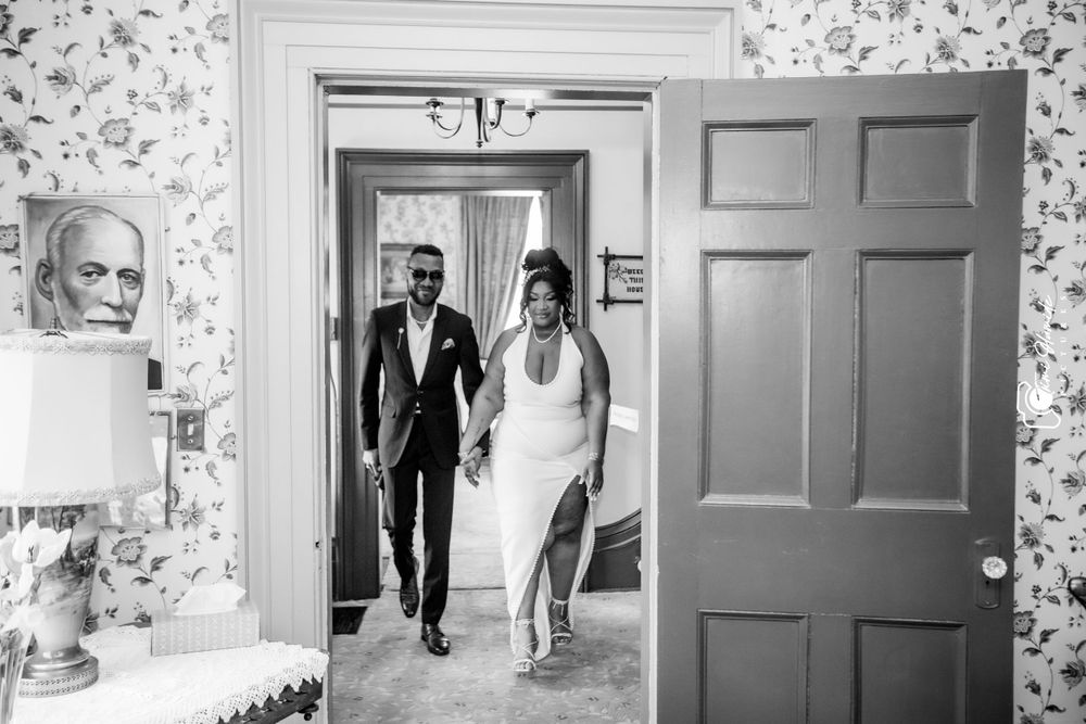 A couple walks through a doorway in formal attire during a wedding ceremony.