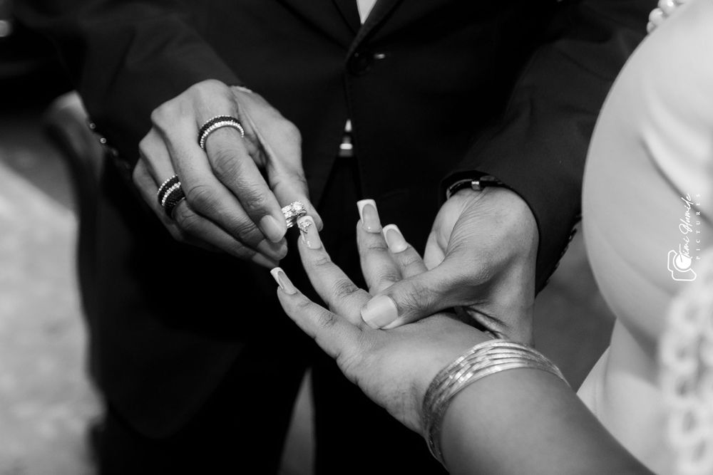 Black and white photo of hands exchanging wedding rings in an intimate ceremony moment.