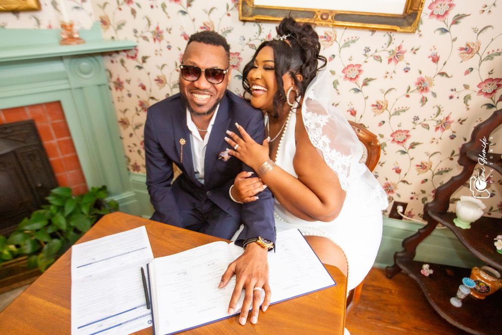 Happy couple showing off their rings while sitting at a desk with signed marriage documents.